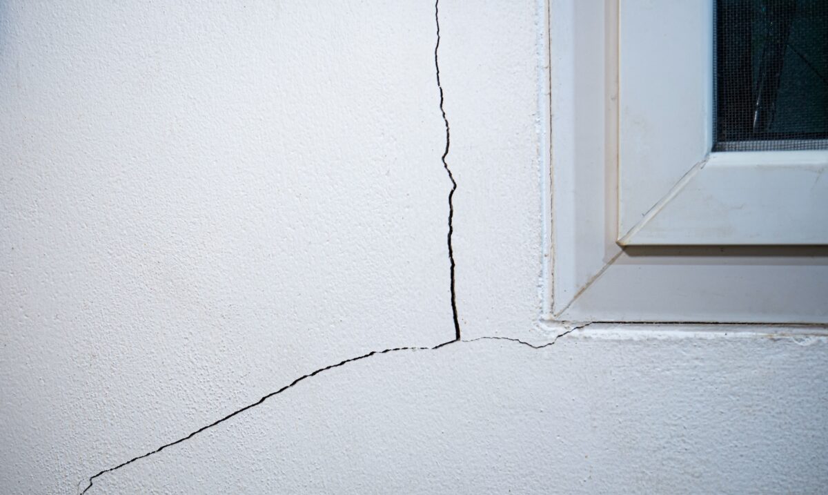 Cracks on the wall. The crack in the cement wall at the window sill, caused by the subsidence of the ground, causing a slit at an oblique angle.