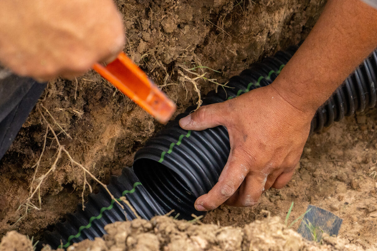 A man working on french drains in the ground. 